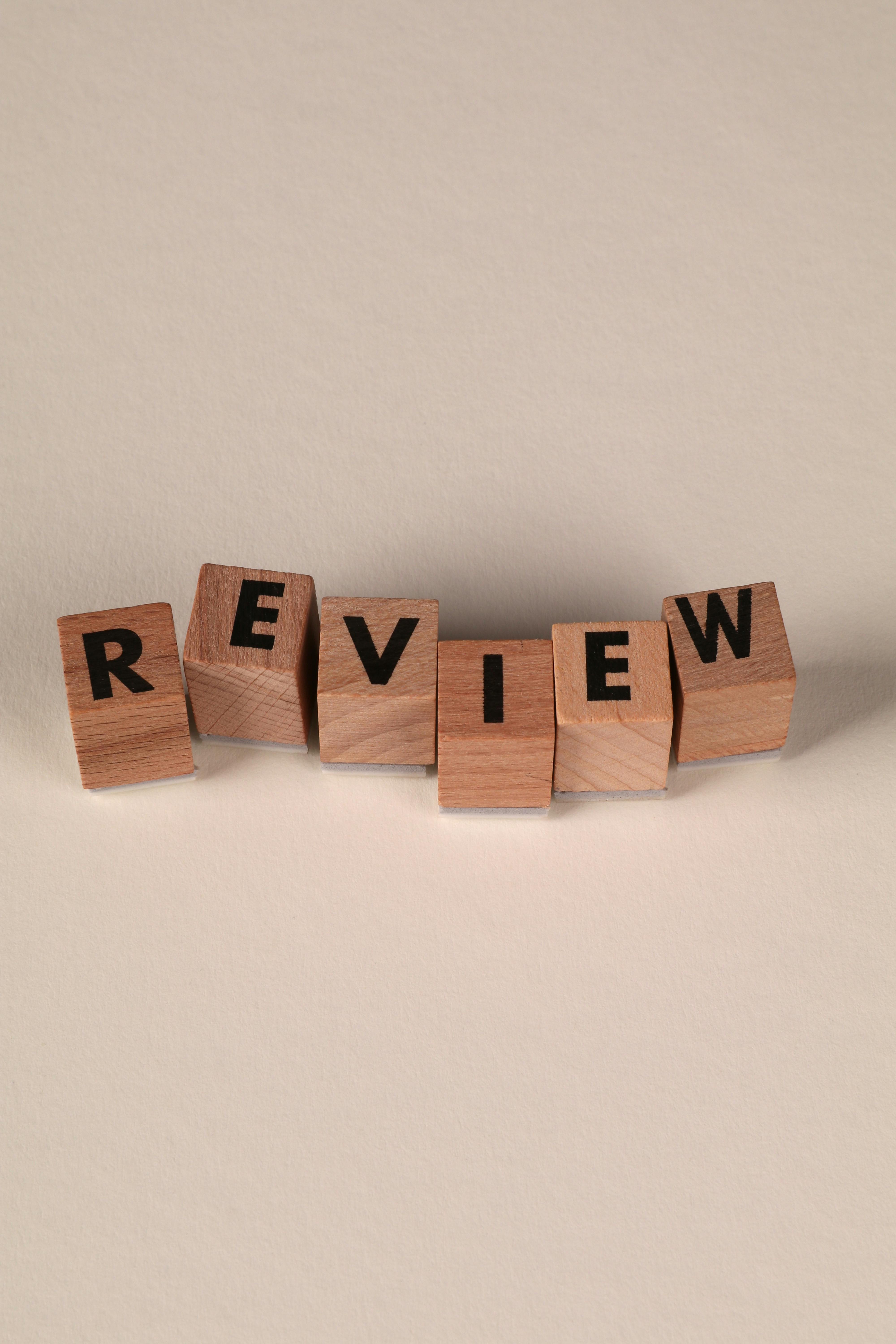 Wooden blocks spelling 'review' on a neutral background, perfect for educational or business concepts.