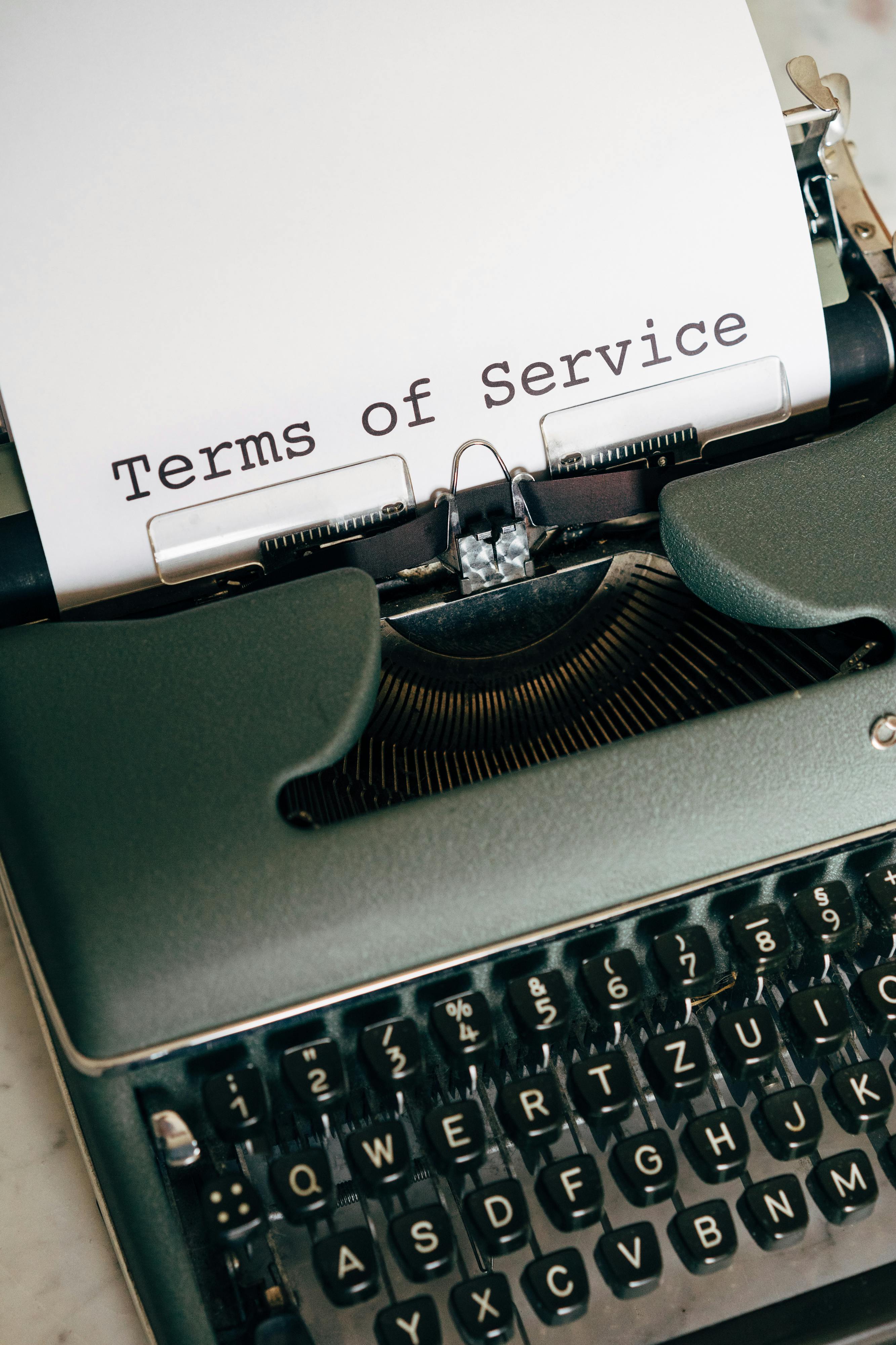 Close-up of a vintage typewriter typing 'Terms of Service' on paper.